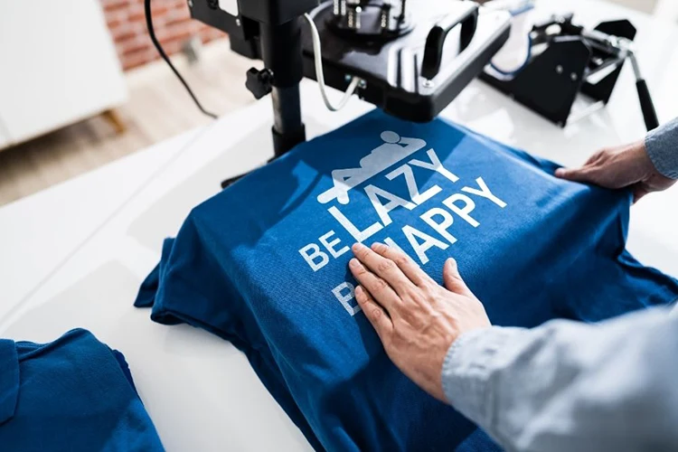 Heat press applying a lettering design to a blue T-shirt