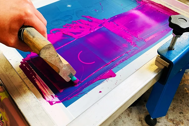 Ink being drawn across a screen during garment screen printing
